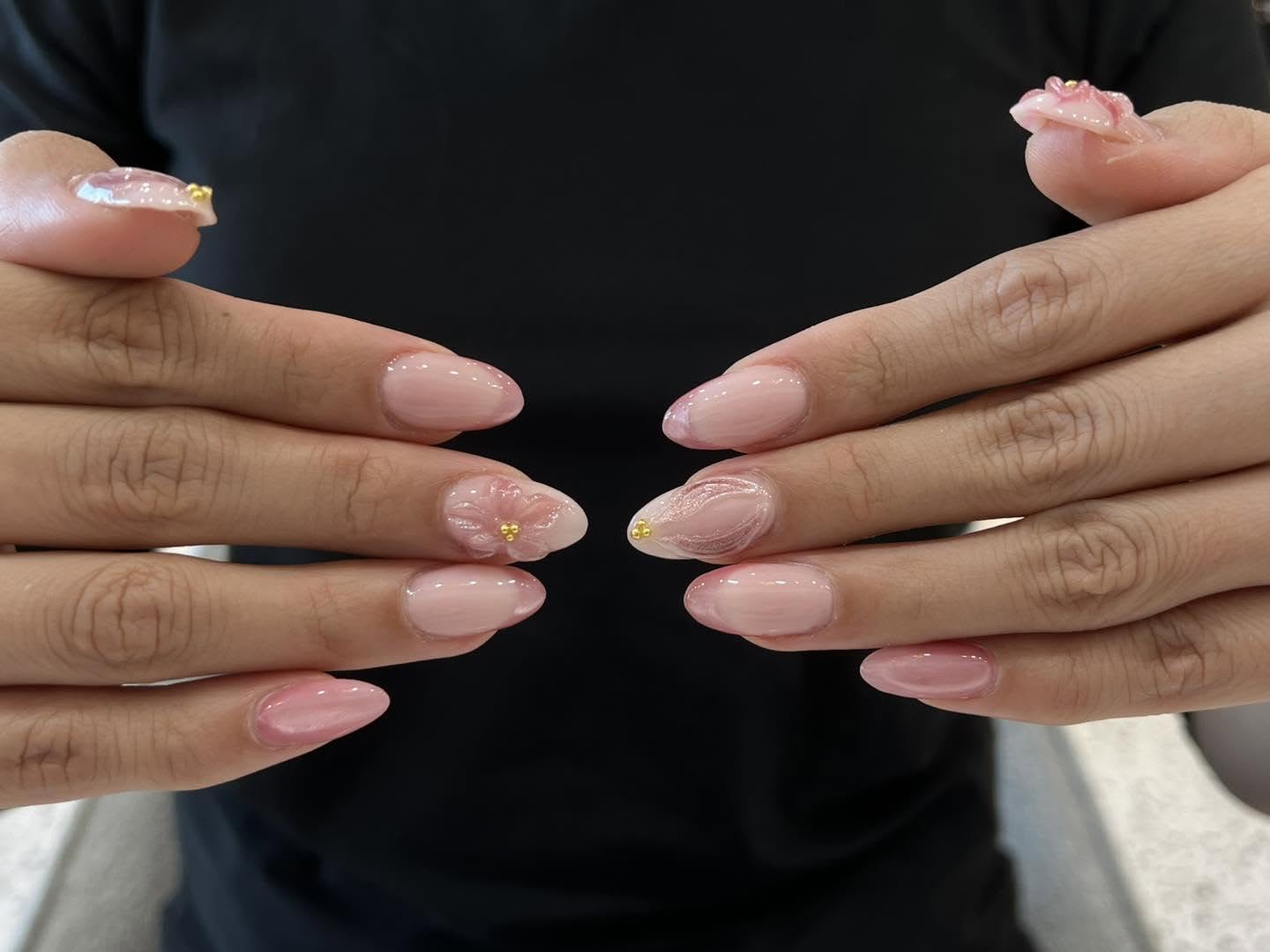 Delicate pink nail art with a floral accent, an example of Beauty Genesis's custom nail work